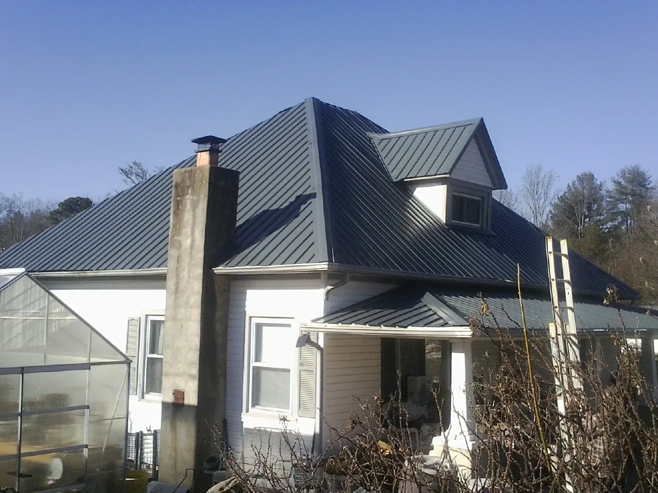 Dark blue standing seam metal roof on a white farmhouse with dormer — Slate & Tile Roof Repair by Roofing Brothers in Hodgenville