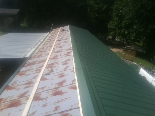 Old rusted panels beside newly installed green metal roofing — Wind Damage Roof Repair by Roofing Brothers in Hodgenville