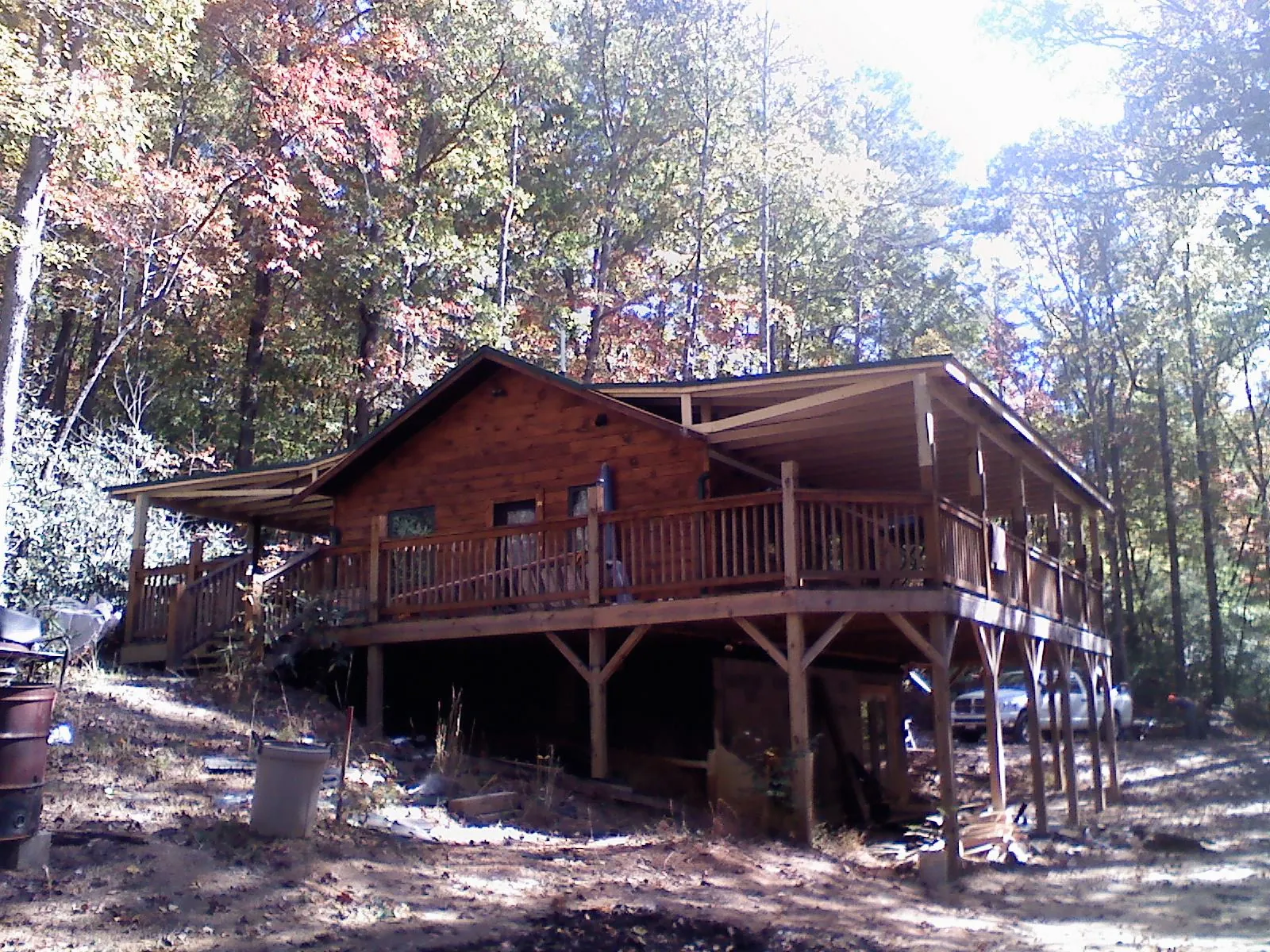 Log cabin with a wraparound porch and metal roof in the fall in Hodgenville