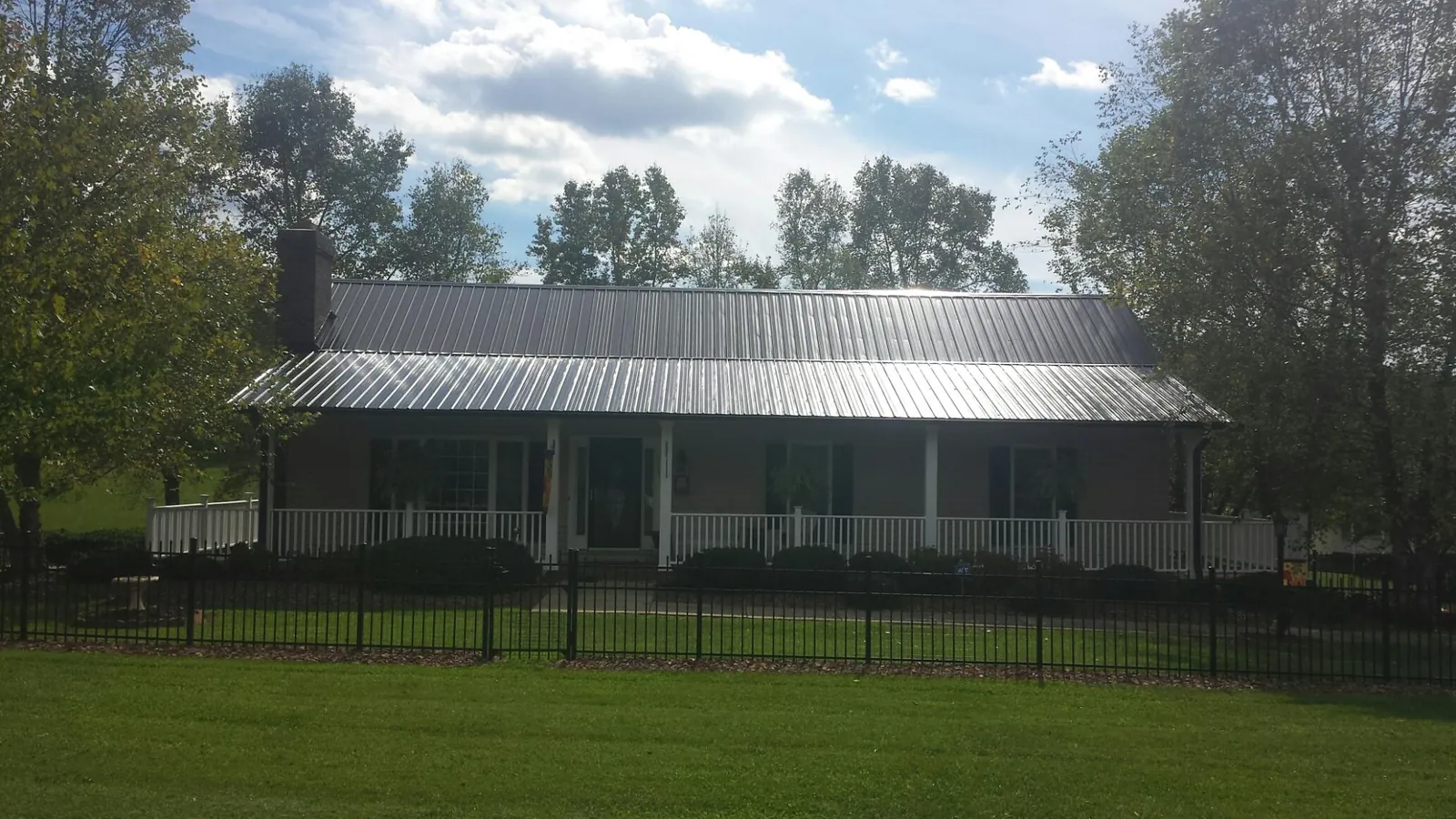 Gray metal roof on a brick ranch with a full width front porch — Gutter Guard Installation work by our crew in Hodgenville