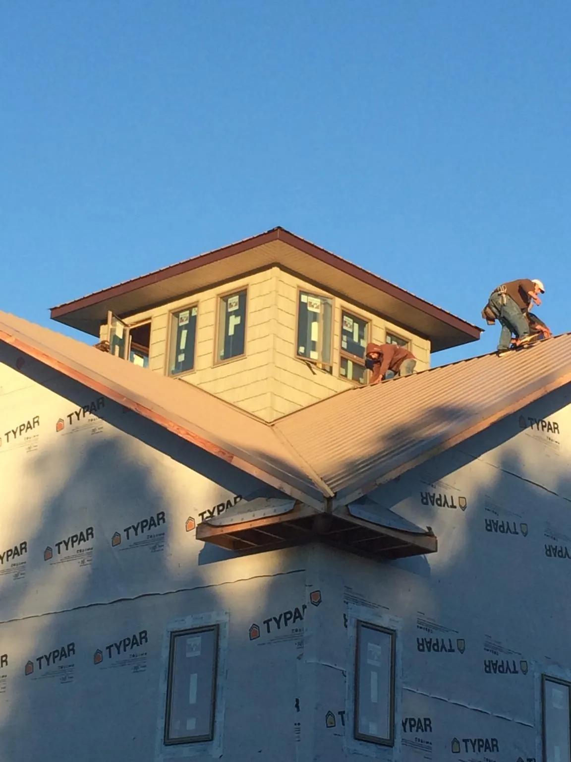 Roofers working around a rooftop cupola on a new metal roof at sunset — Roof Waterproofing in Hodgenville by Roofing Brothers